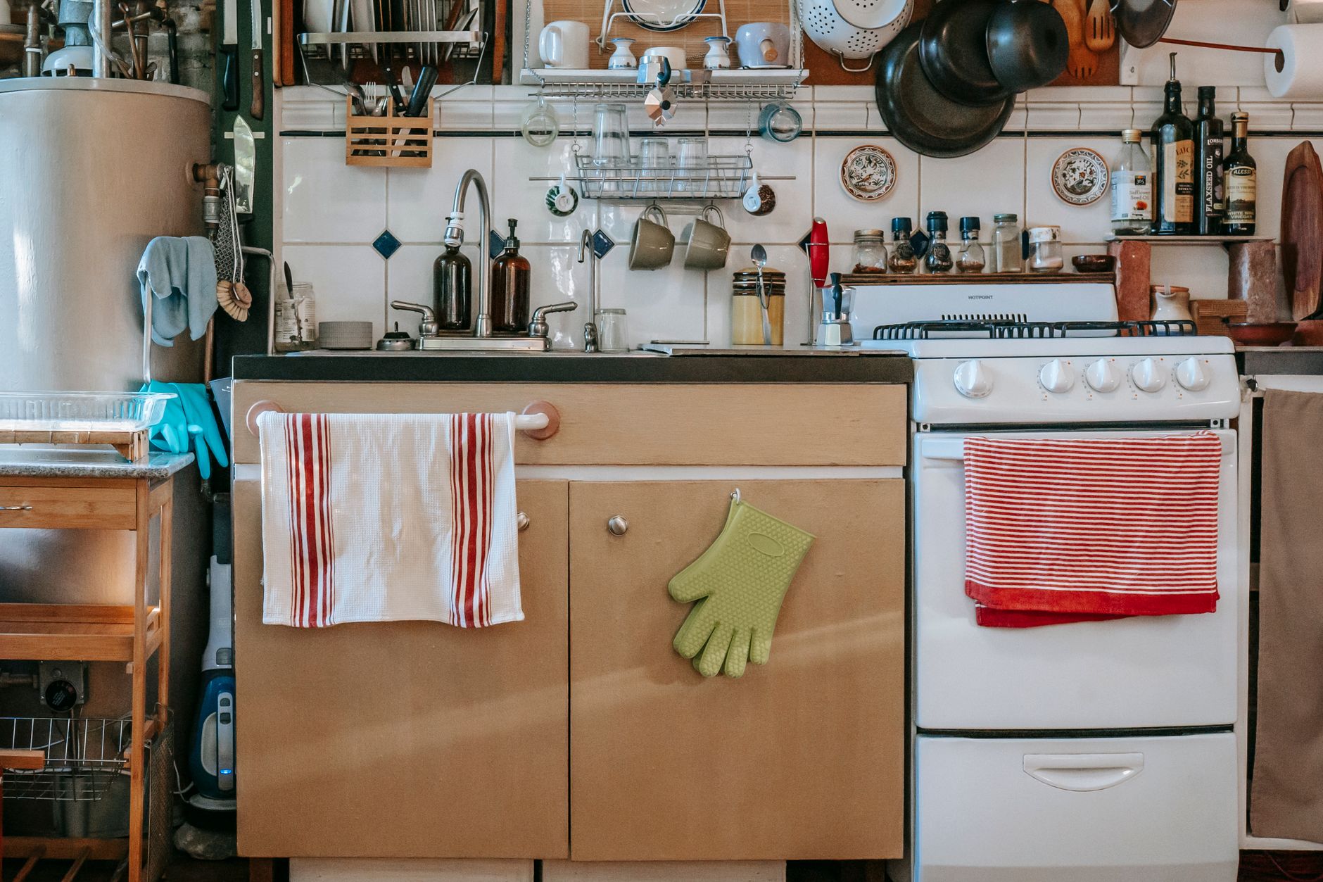 Folded kitchen towels and a dishcloth beside a sink in a warm home kitchen