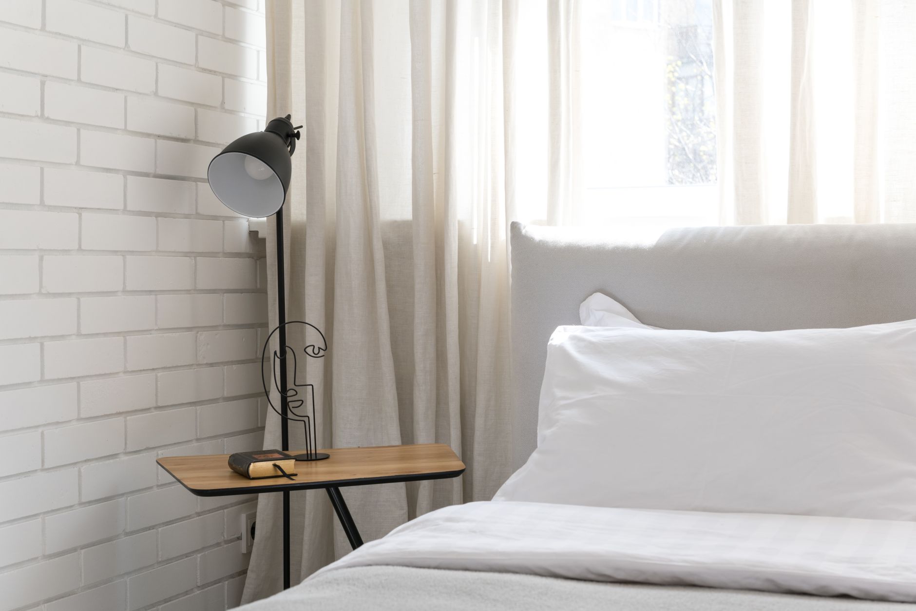 A simple bedside table with a lamp, book, and a few neatly kept essentials